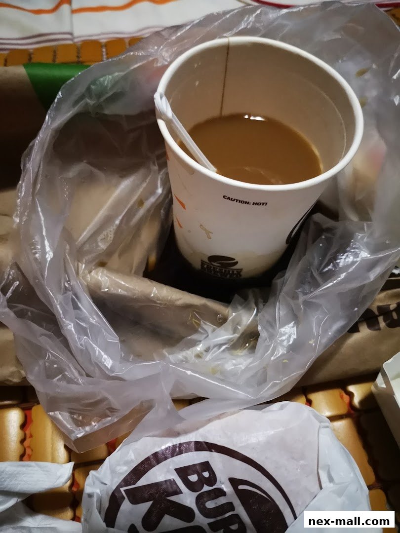 A Burger King paper cup with coffee and a burger in a plastic bag.