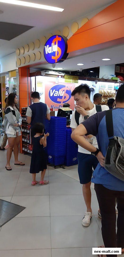 People are queuing at the entrance of a shop called Valu, with blue shopping baskets visible.