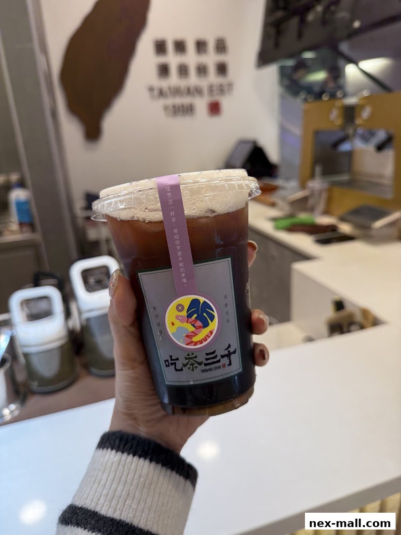 A hand holds a cup of iced tea from CHICHA San Chen with Taiwanese branding.