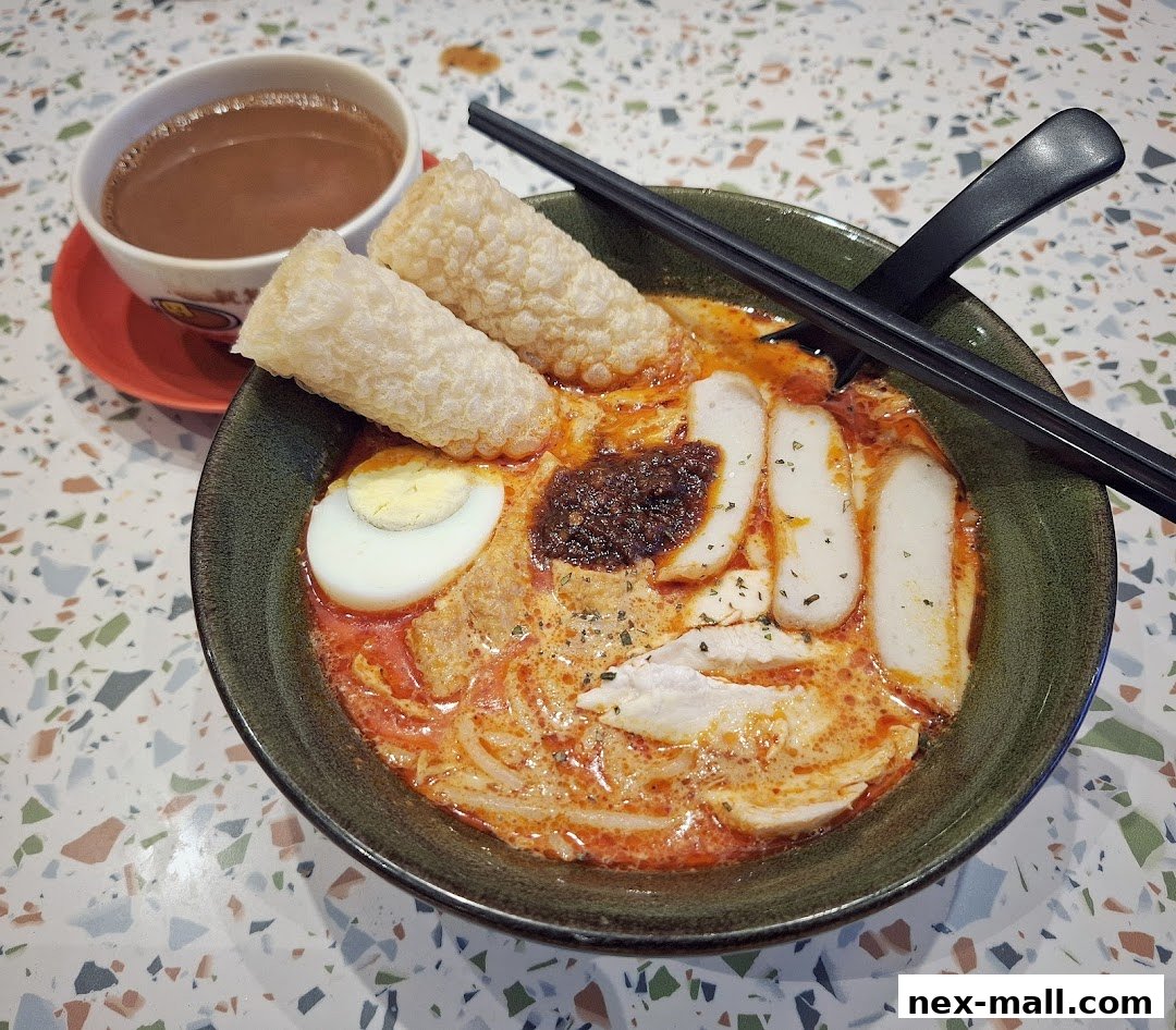 A delicious bowl of Laksa with a side of coffee, presented on a speckled table.
