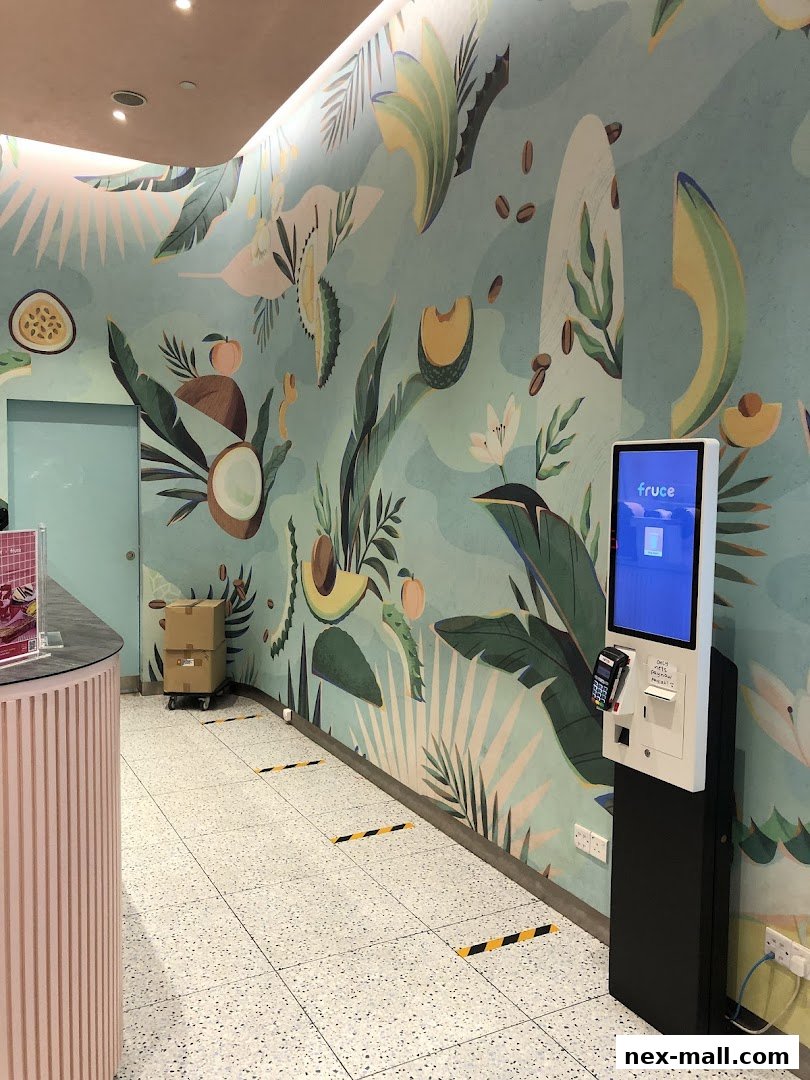 Interior of a Fruce NEX shop with a vibrant fruit-themed mural and a self-order kiosk.