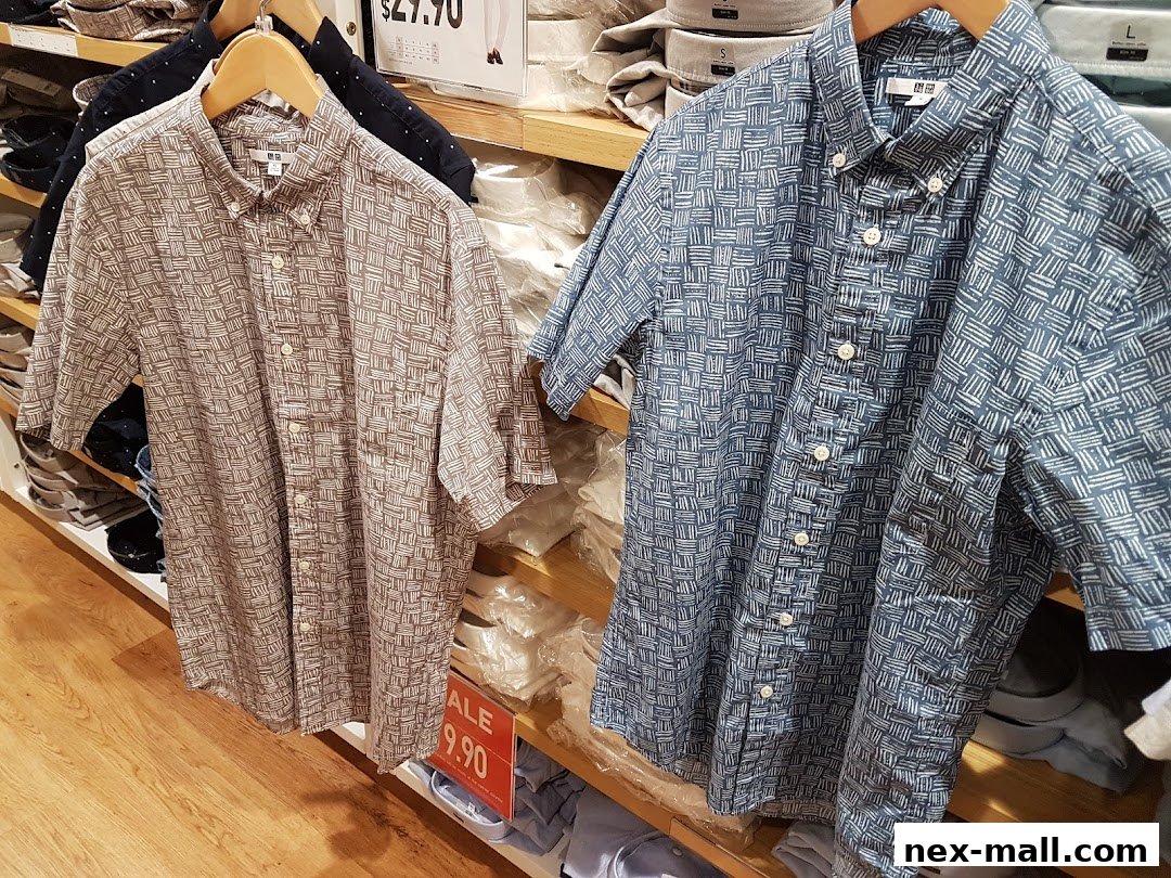 Two patterned short-sleeved button-up shirts displayed on hangers in a retail store.