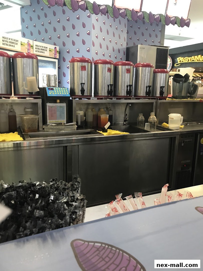 A counter at a LiHO TEA shop with large dispensers and various drink ingredients.