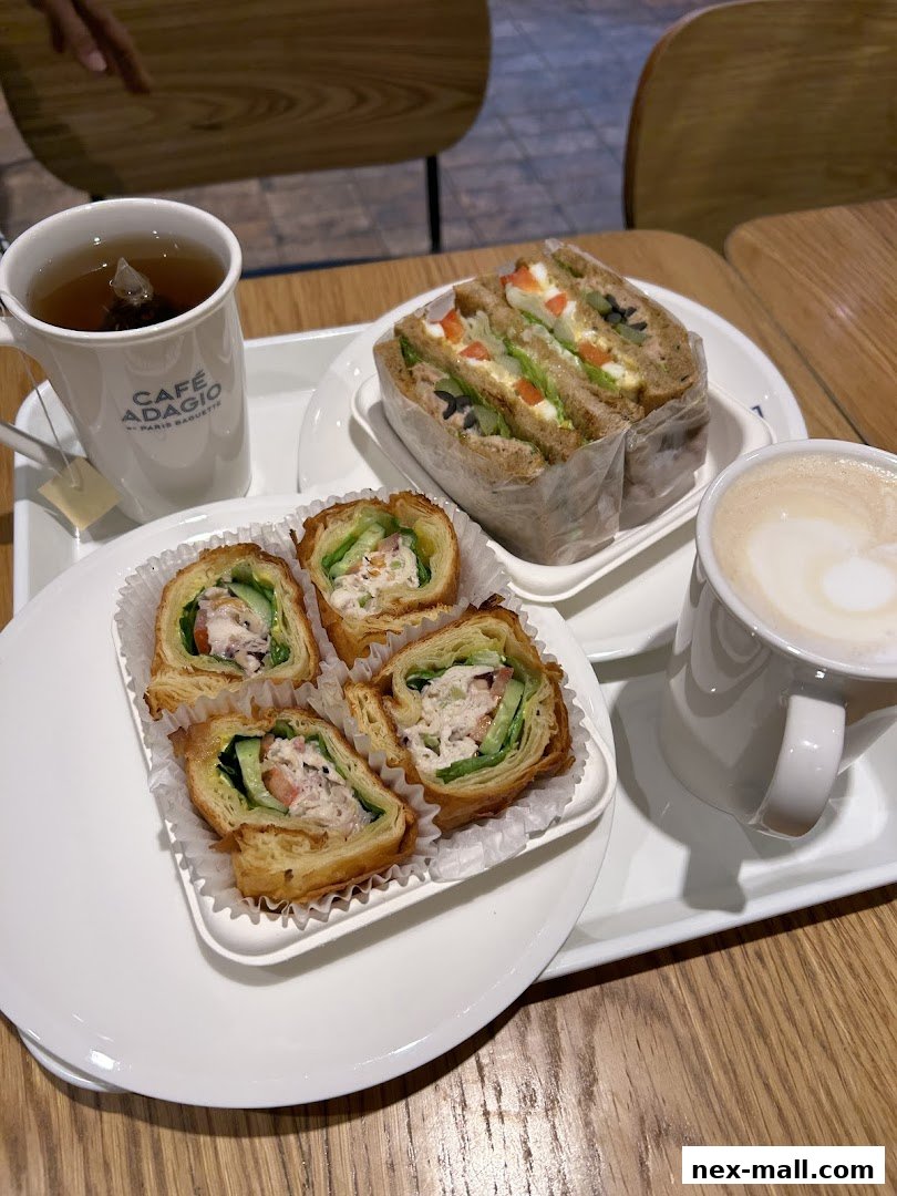 A tray with tea, coffee, sandwiches, and pastry rolls from Paris Baguette.