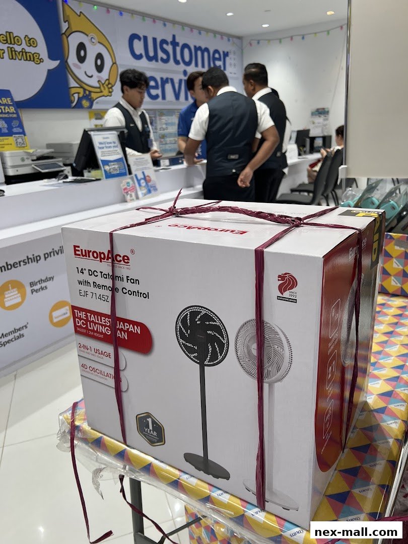 A boxed EuropAce fan is displayed in front of a customer service counter with staff.