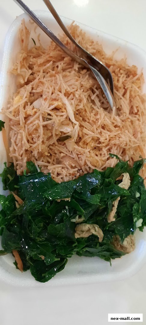 A close-up shot of a takeout container filled with stir-fried noodles and a side of cooked green vegetables.
