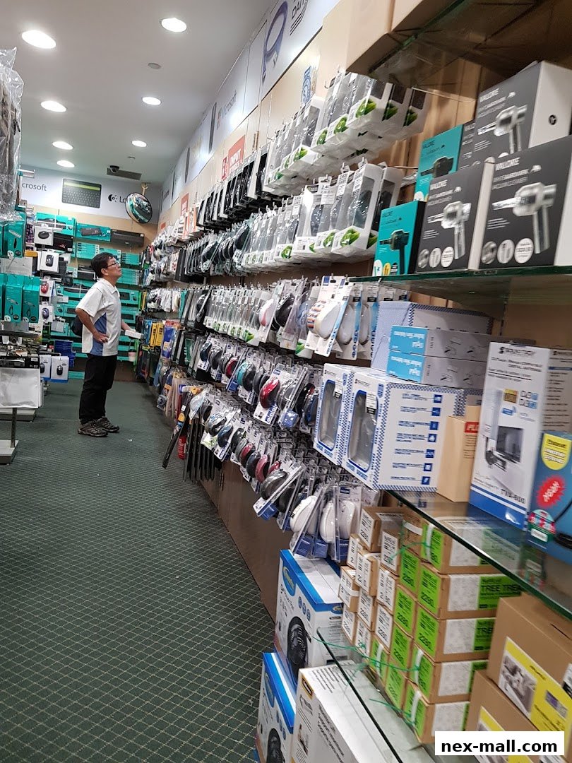A person stands in an electronics store aisle filled with computer accessories and gadgets.