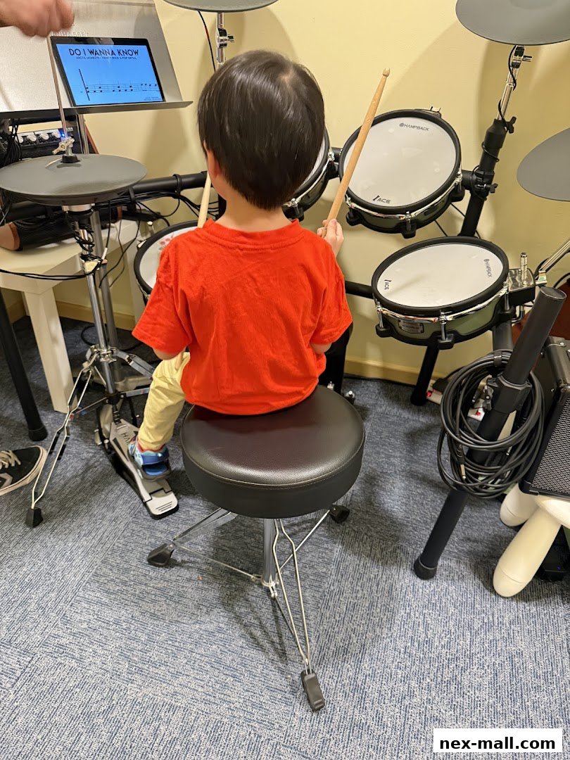 A child in an orange shirt learns to play drums at Aureus Academy.