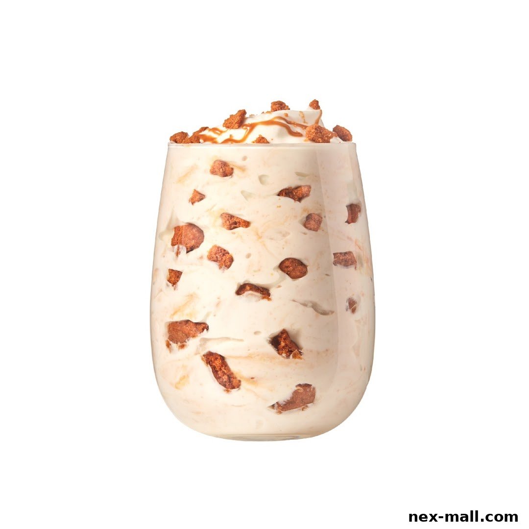 A creamy dessert with cookie crumbles and caramel drizzle in a glass.