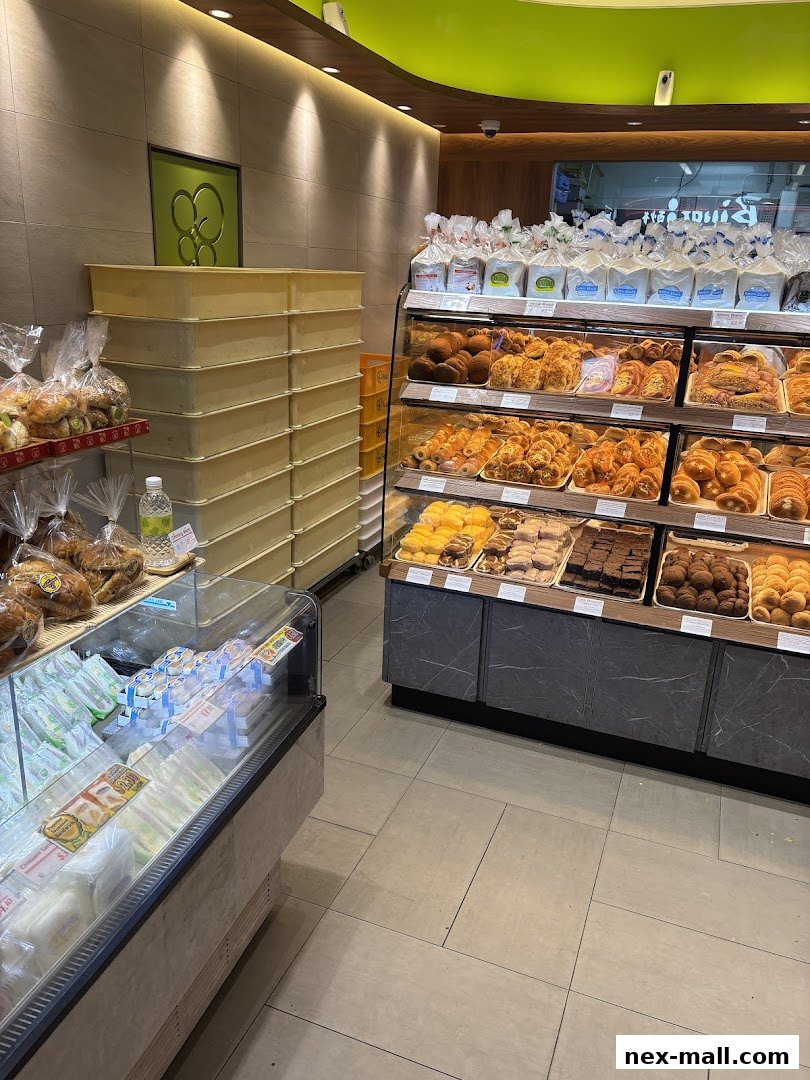 Interior view of a bakery with a display of fresh bread, pastries, sandwiches, and packaged goods.
