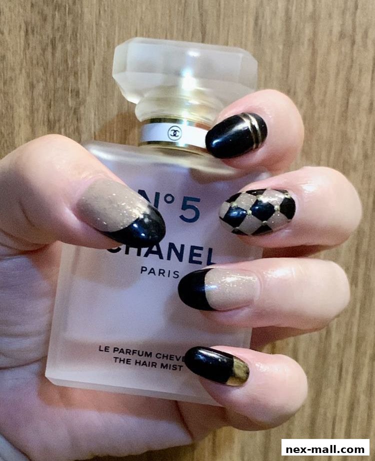 A hand with stylish black and nude nails holds a Chanel No. 5 hair mist bottle.