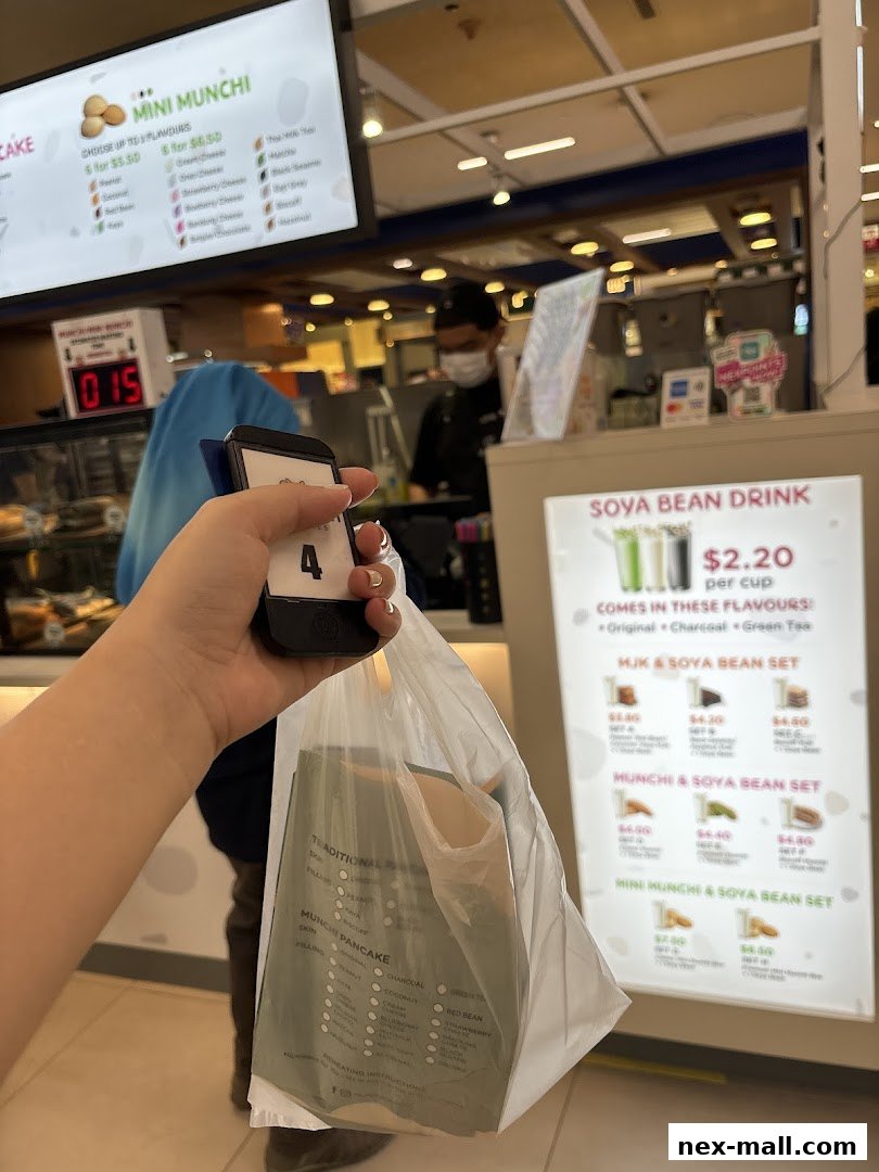 A person holds a bag with a pancake menu and a number 4 ticket at Munchi Pancakes.