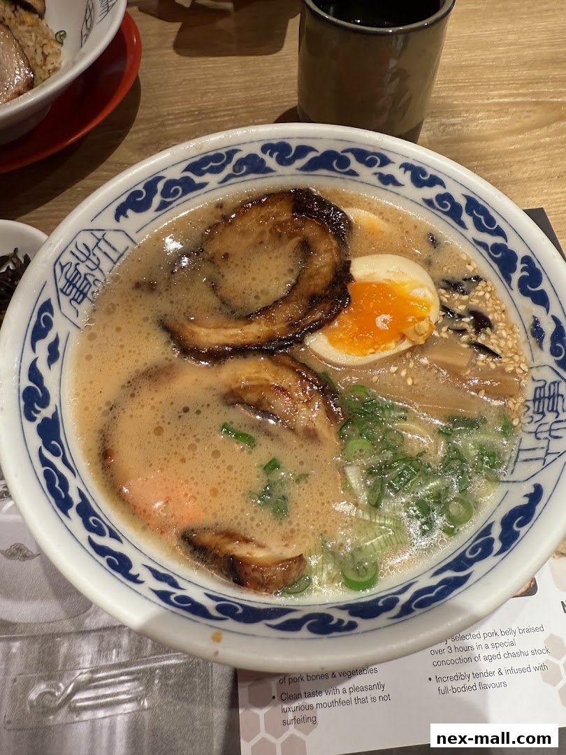 A close-up of a steaming bowl of ramen with pork, egg, and green onions.