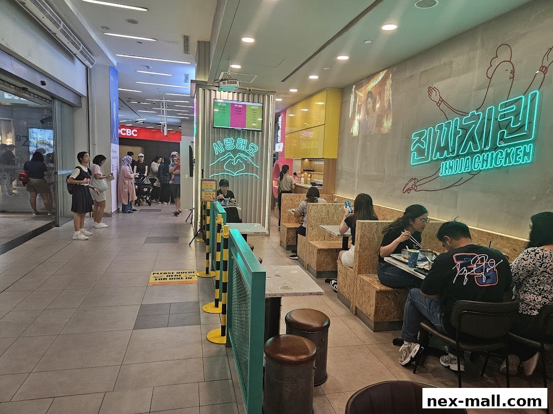 Interior view of JINJJA Chicken restaurant with customers dining and a queue forming.