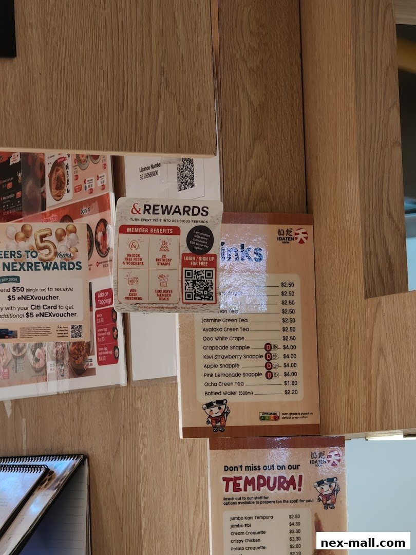A menu board displaying drinks and tempura options with prices at Idaten Udon.