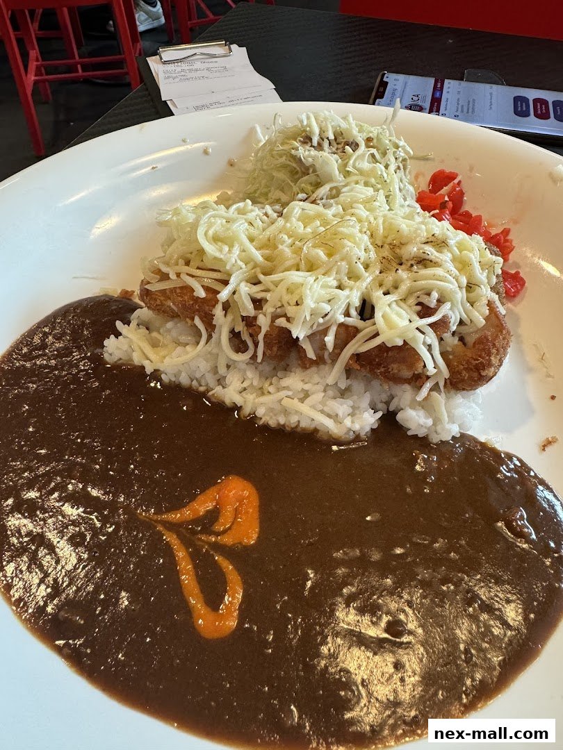A plate of Japanese curry with rice, fried chicken, shredded cabbage, and cheese.