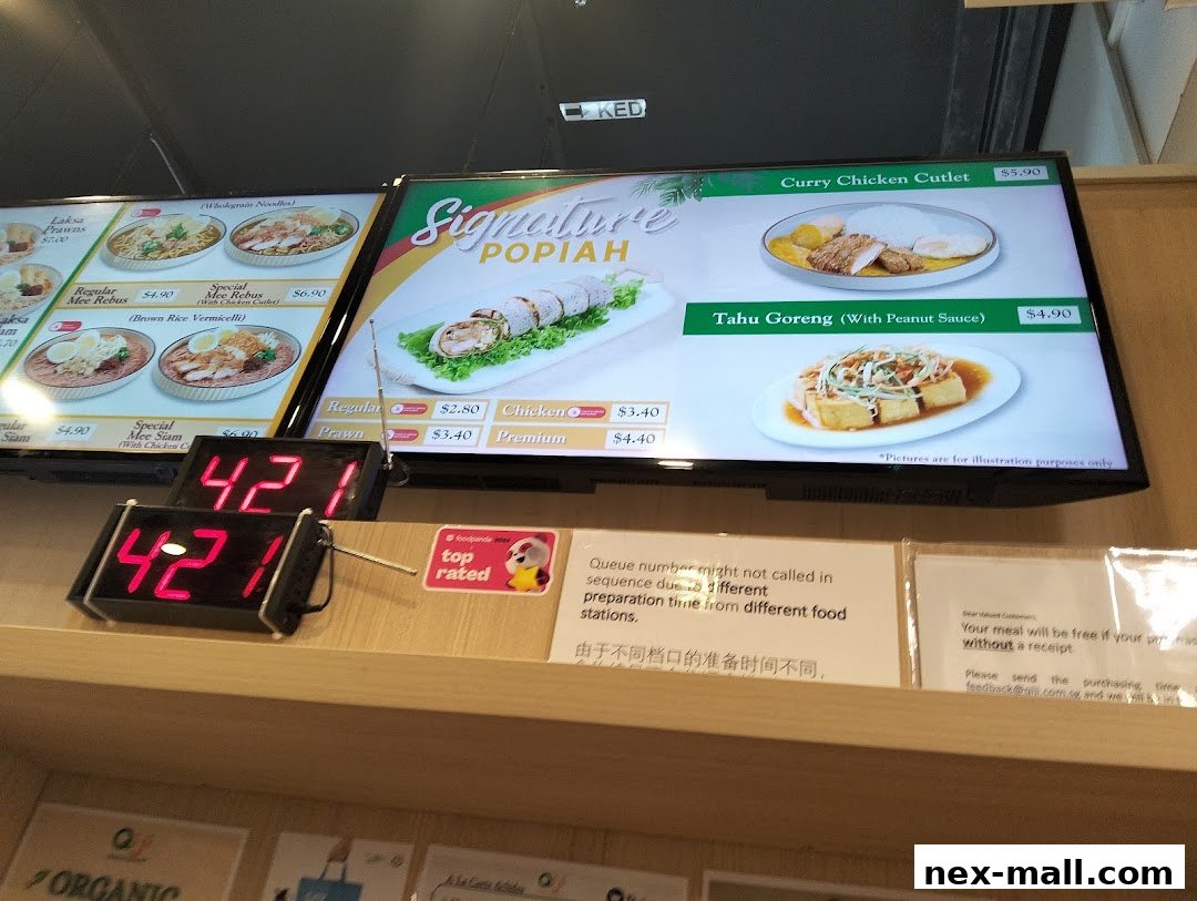 A digital menu board displaying various food items and prices, with a queue number display below.