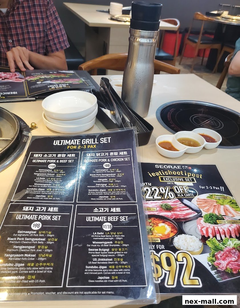 A table at a Korean BBQ restaurant with menus, bowls, and a thermal flask.
