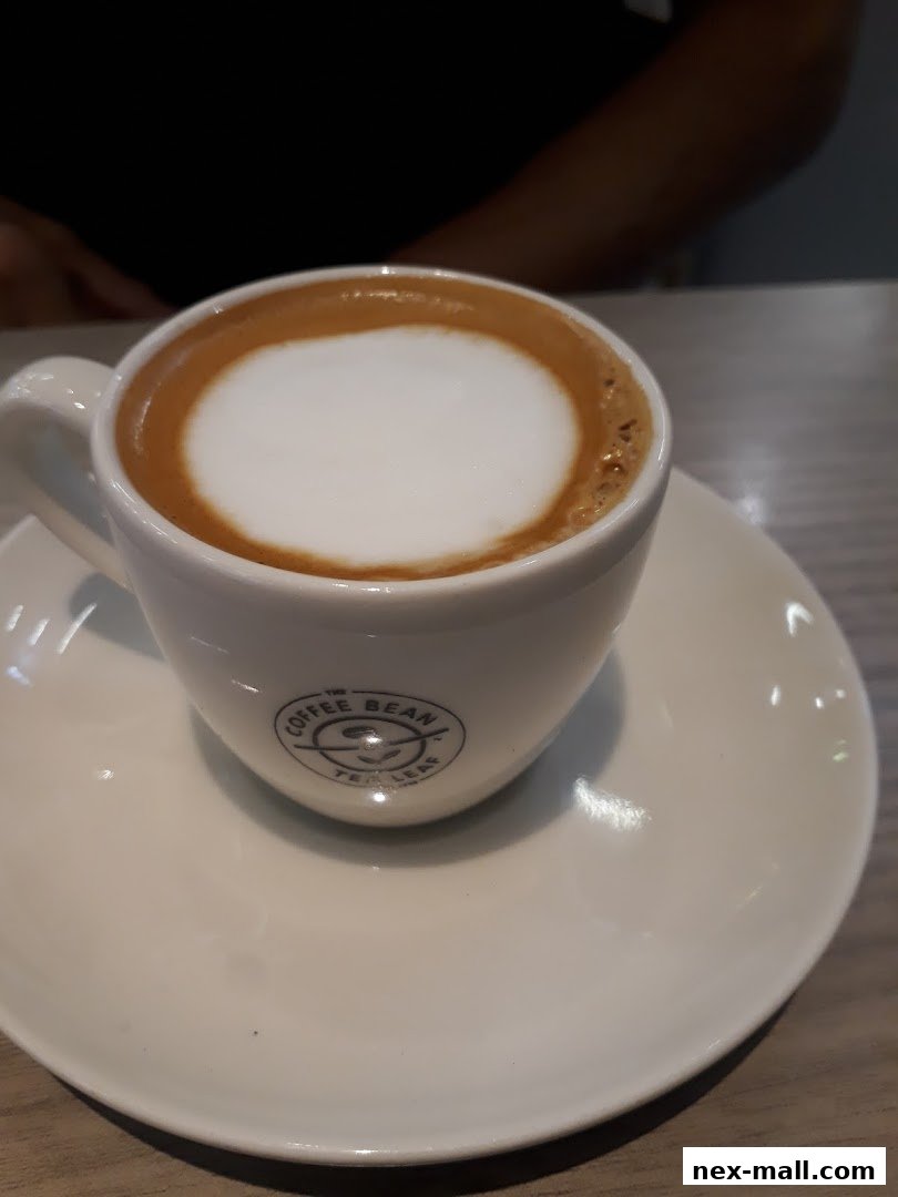 A close-up shot of a cappuccino with frothy milk in a white cup and saucer.