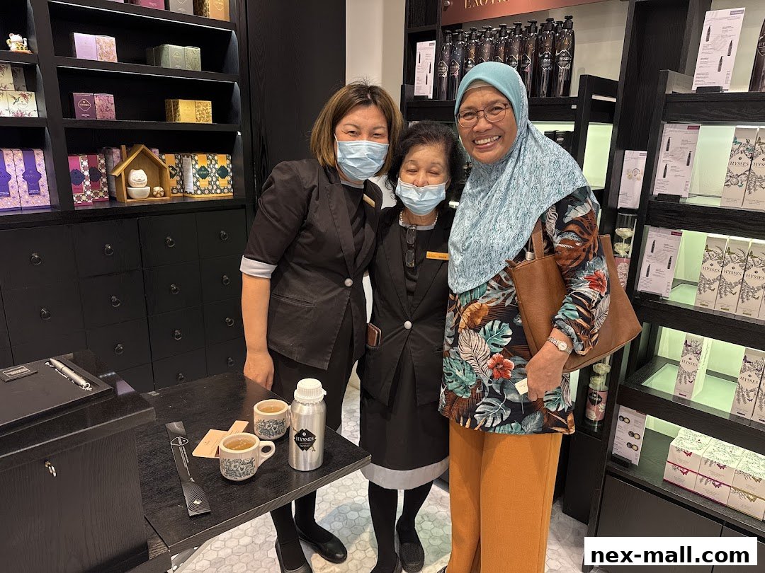 Three smiling people, two staff and one customer, pose in a well-lit shop with shelves of products.