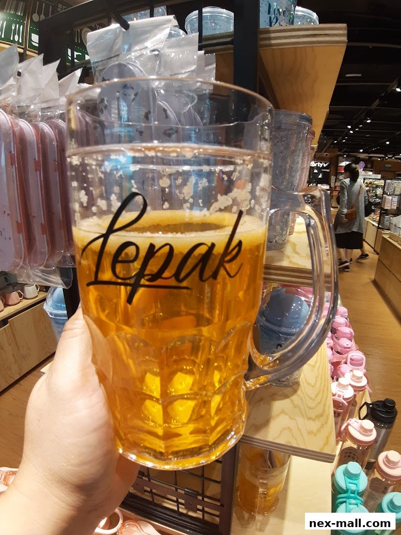 A hand holds a large beer mug with the word 'lepak' written on it, in a store.