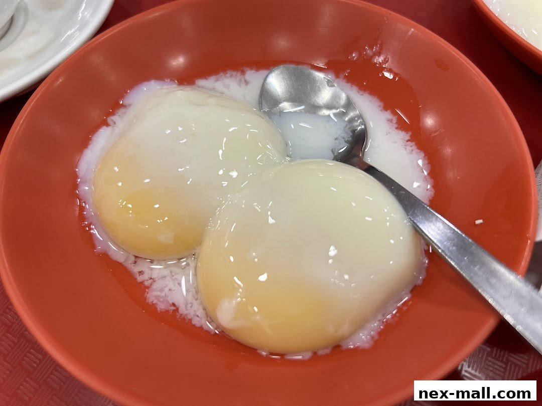 A close-up shot of two perfectly soft-boiled eggs in an orange bowl with a spoon.