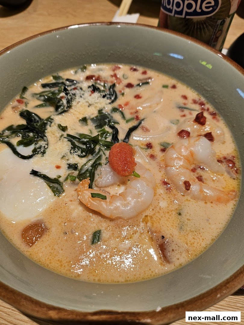 A close-up shot of a delicious bowl of udon noodles with shrimp and a creamy broth.