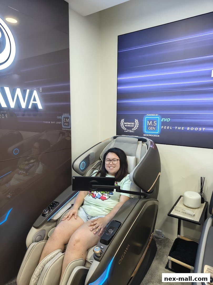 A woman smiles while sitting in a modern OGAWA massage chair with a tablet.