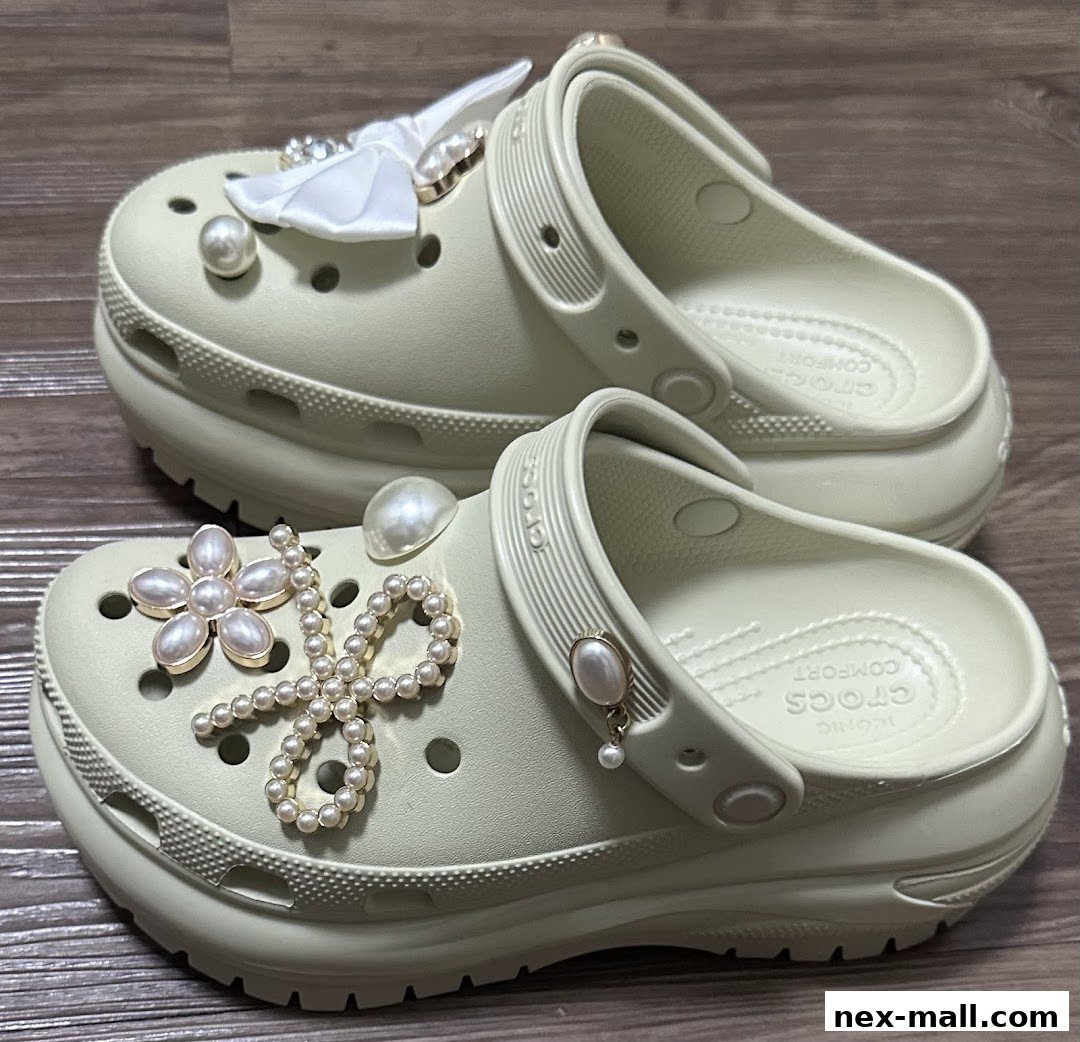 A pair of light green Crocs adorned with pearl and bow embellishments.