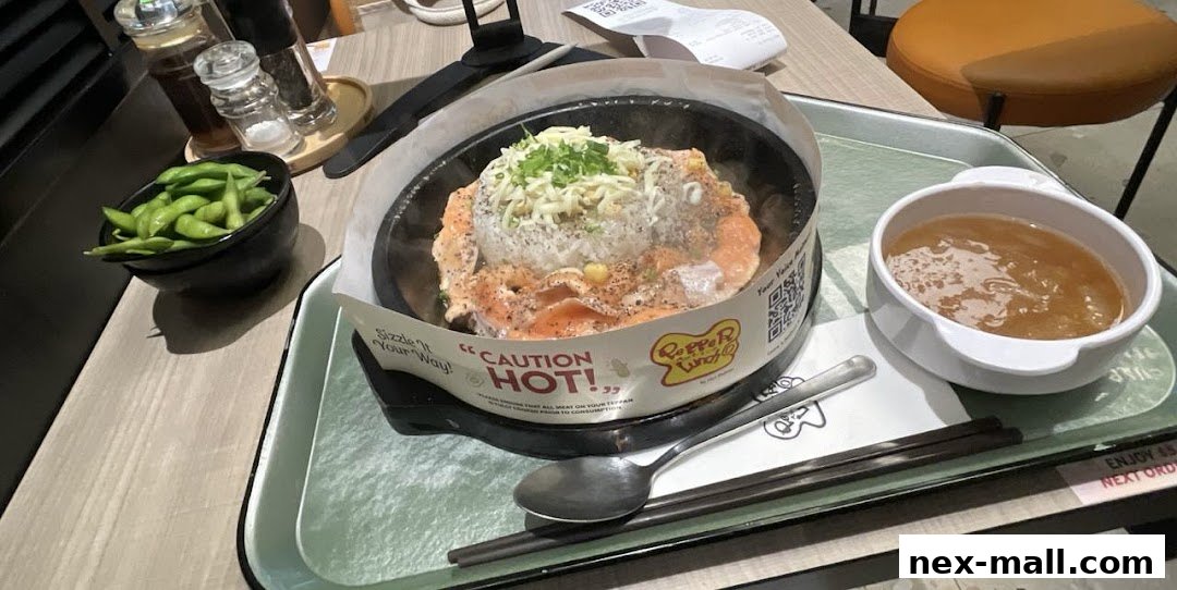 A sizzling hot plate meal with salmon, rice, and edamame, served with soup.