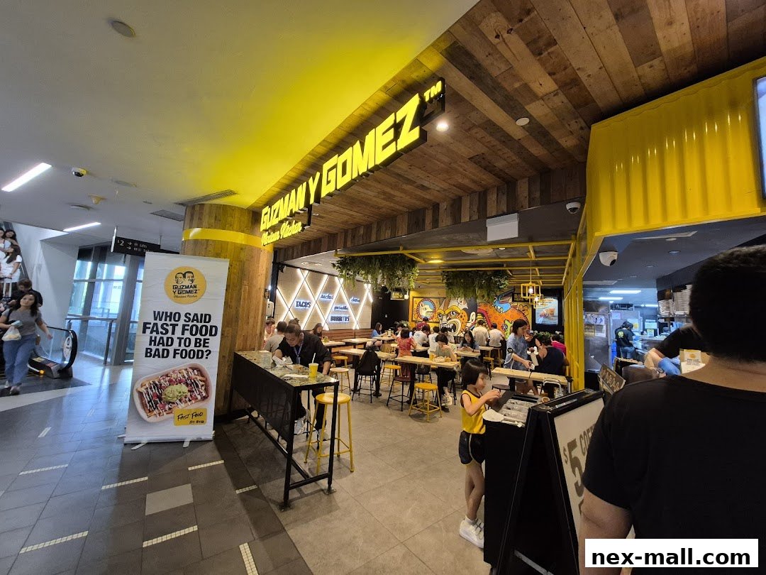 Interior view of a Guzman y Gomez restaurant with customers dining and a promotional banner.