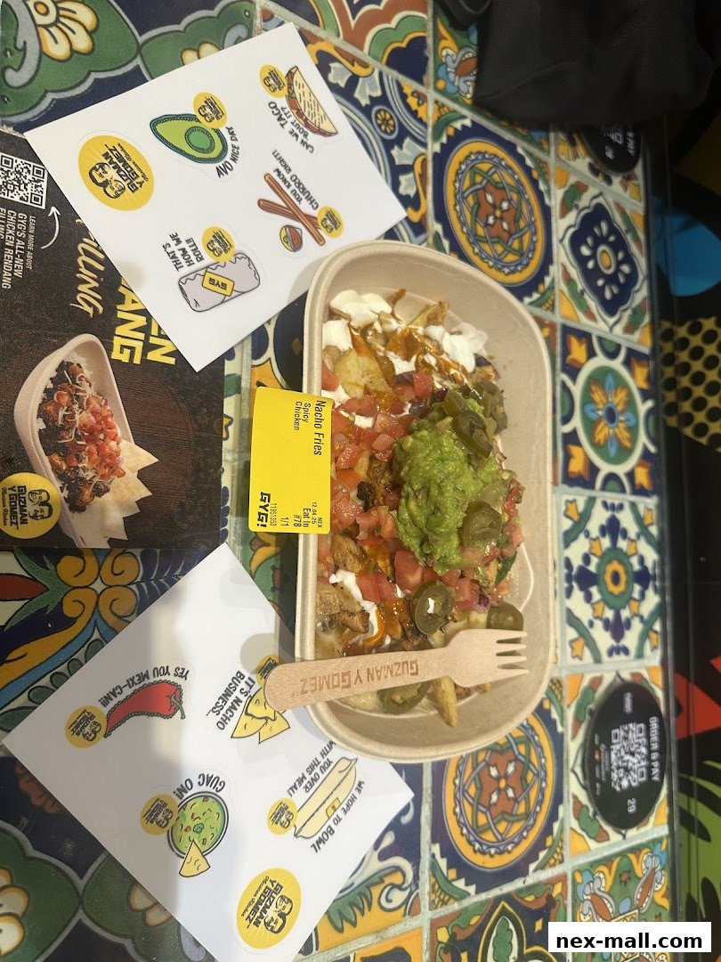 A bowl of Nacho Fries with toppings, stickers, and a fork from Guzman y Gomez.