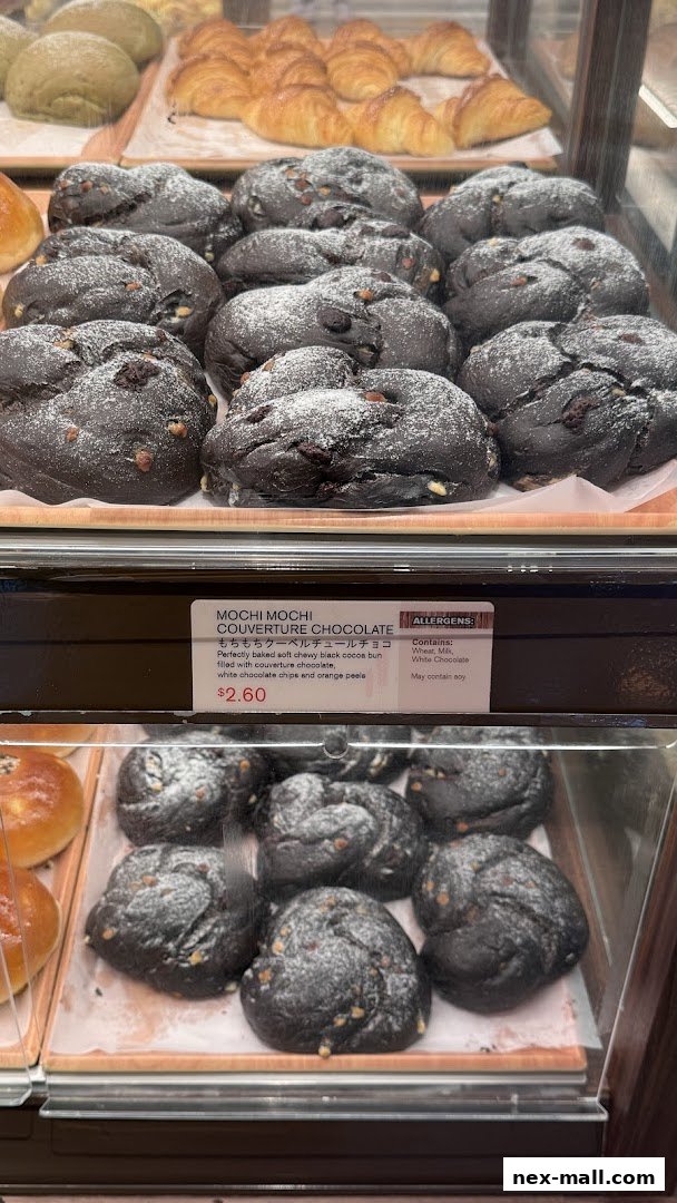 A display of freshly baked dark chocolate mochi buns dusted with powdered sugar.