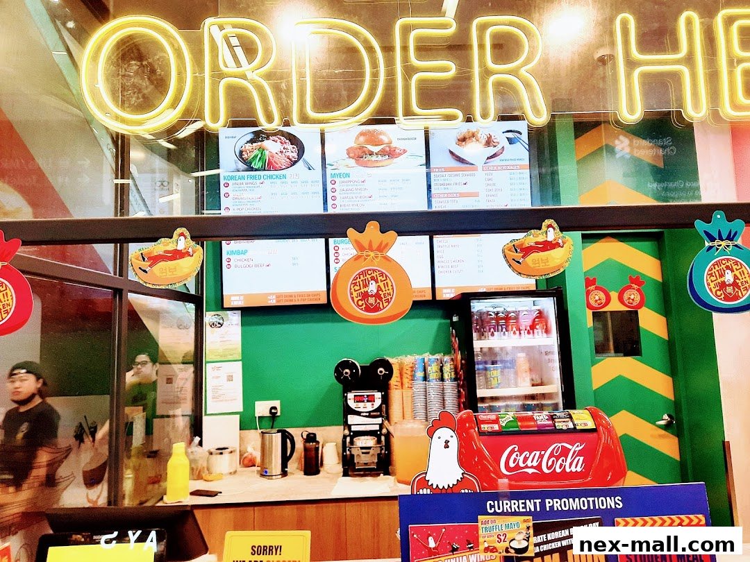 A view of the counter and menu boards at JINJJA Chicken, with neon signage.