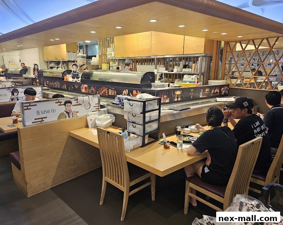 Diners seated at a sushi bar with anime-themed decorations and a long sushi display.