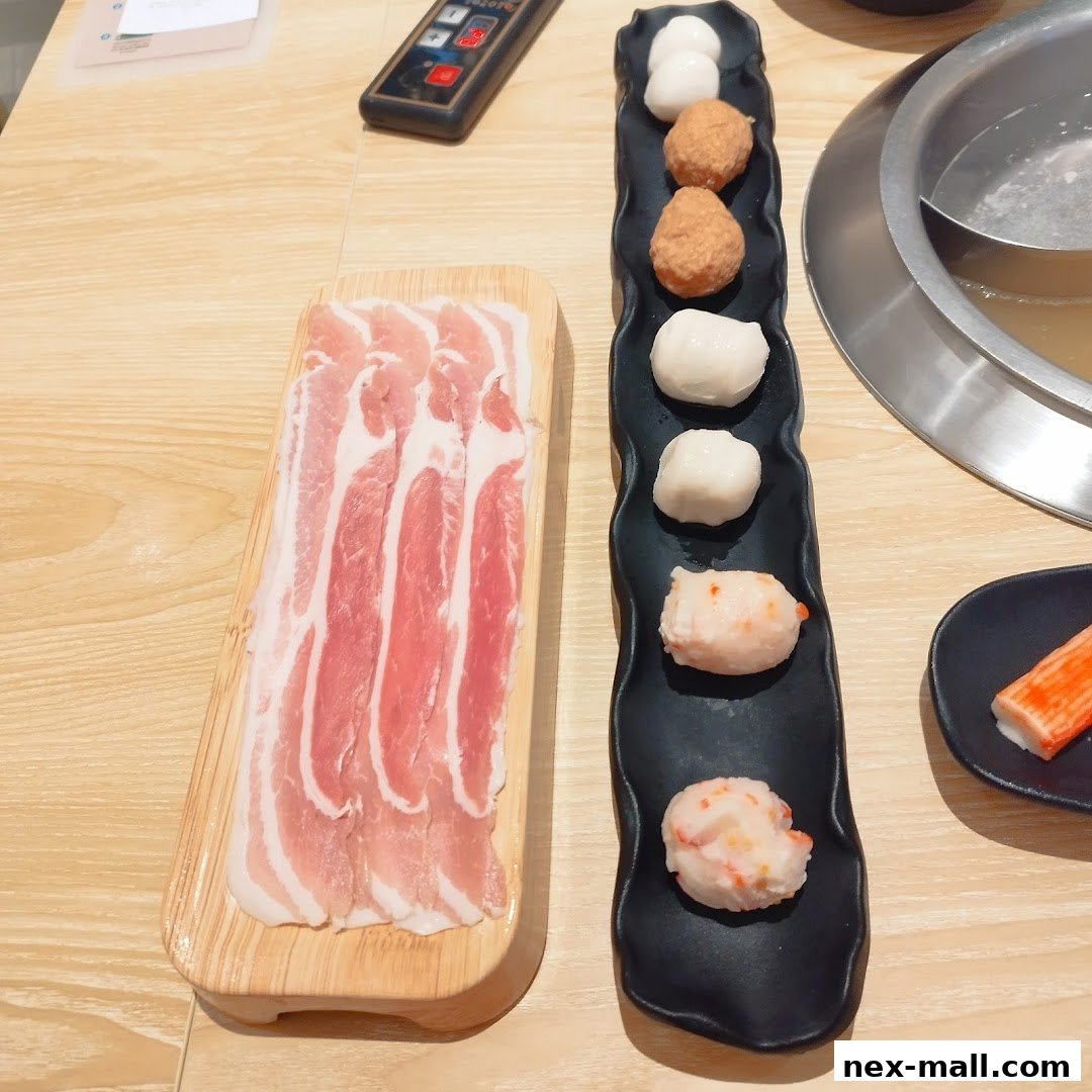 A close-up of thinly sliced pork belly and assorted meatballs for hot pot.