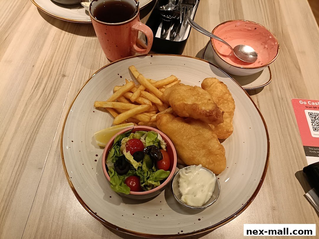 A plate of fish and chips with a side salad, tartar sauce, and a cup of tea.
