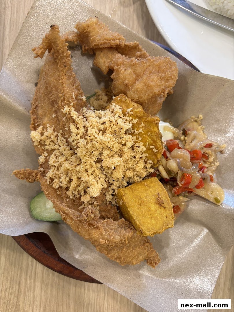 A close-up of a delicious Ayam Penyet dish with crispy fried chicken and sambal.