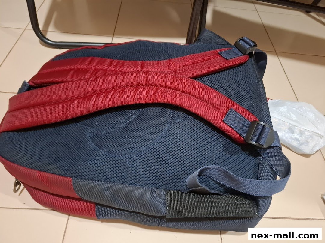 A close-up view of the back of a red and navy blue backpack, showing straps and mesh.