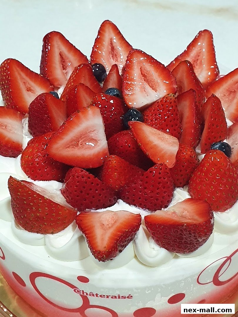 A close-up of a Châteraisé cake generously topped with fresh strawberries and blueberries.