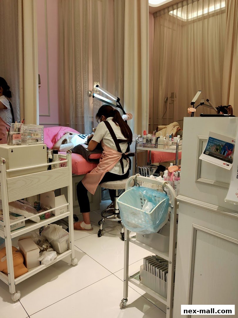 A lash technician applies eyelash extensions to a client in a clean, well-lit salon.