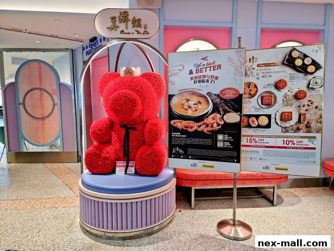 A red teddy bear decoration with a crown stands near promotional posters for Beauty in The Pot.