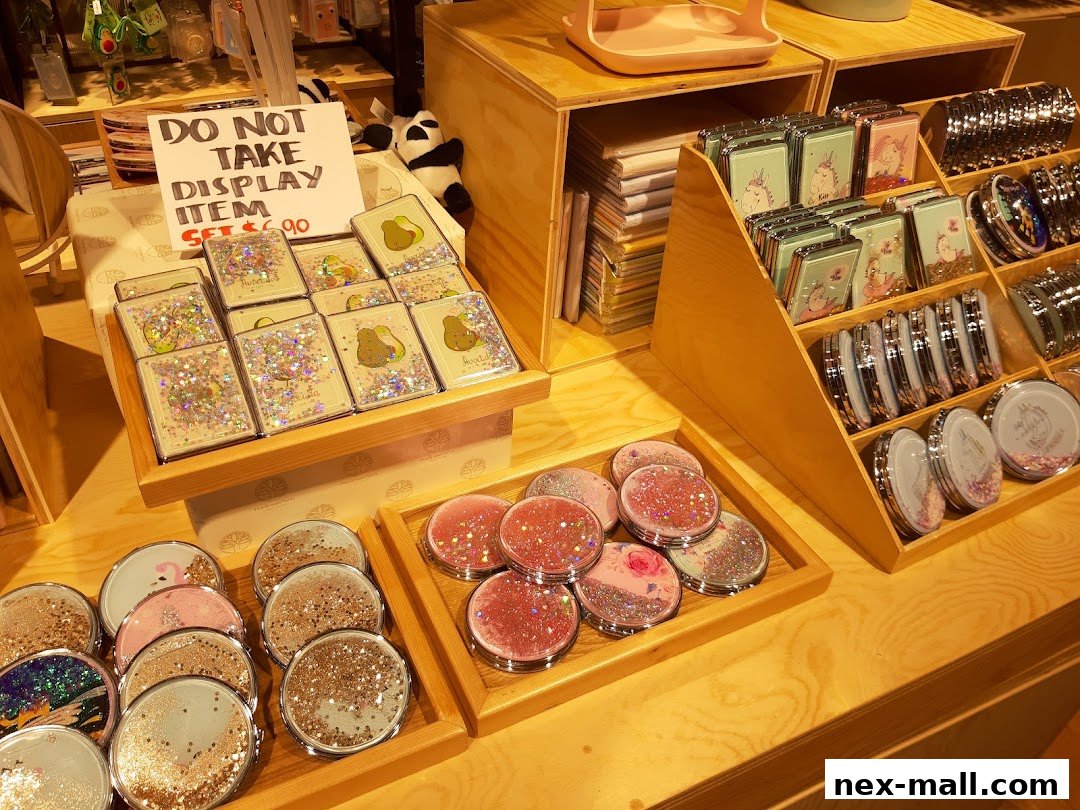 A display of compact mirrors with glitter and cute designs, including avocados and unicorns.