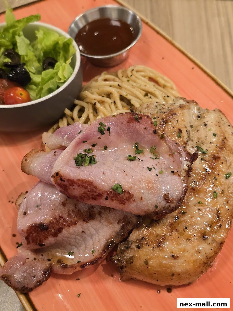 A plate of grilled chicken, bacon, spaghetti, and a side salad with dipping sauce.