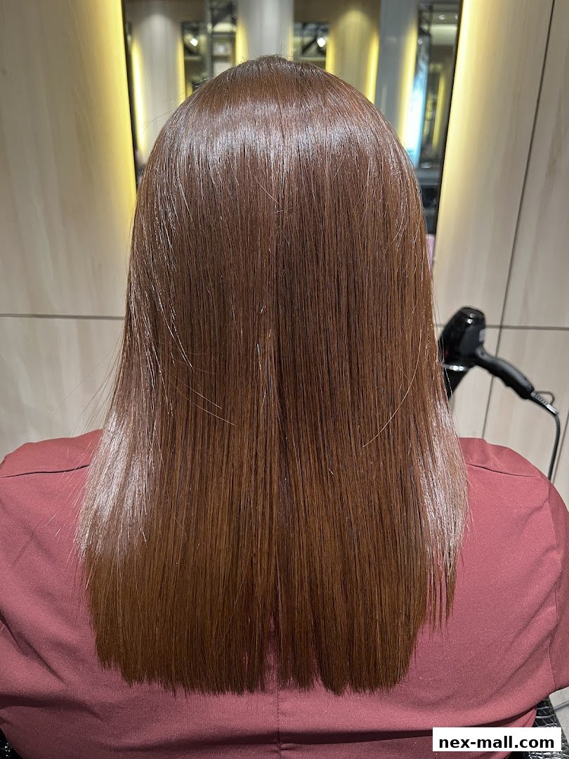 A person's back with long, straight, shiny brown hair, styled in a salon.