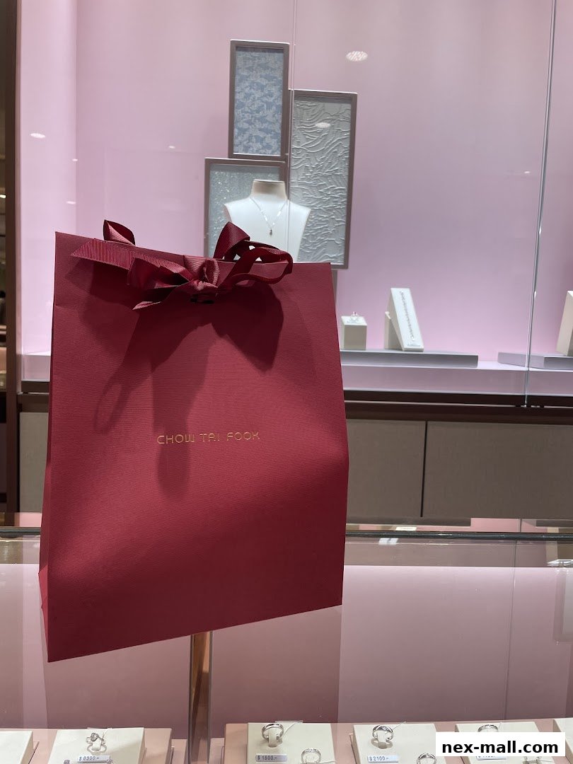 A red shopping bag with a bow in front of a jewelry store display.