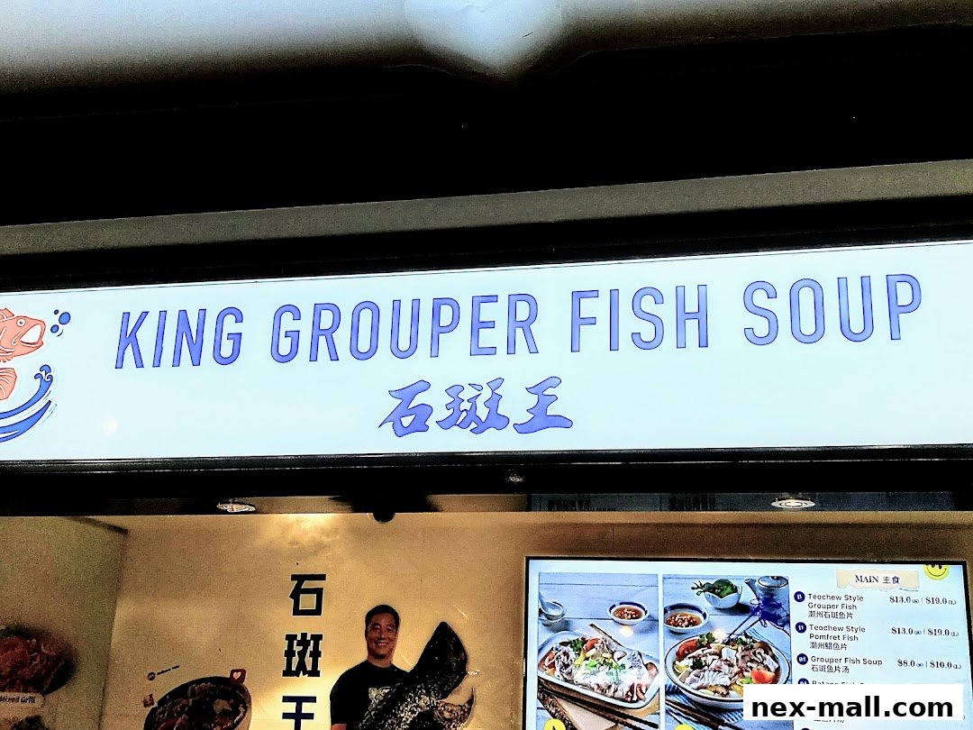 A brightly lit sign for King Grouper Fish Soup with a menu display below.