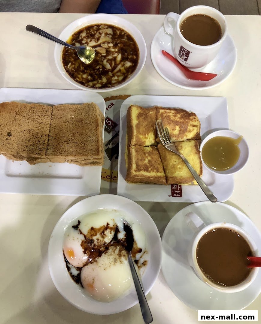 A spread of traditional Singaporean breakfast items including kaya toast, soft-boiled eggs, and coffee.