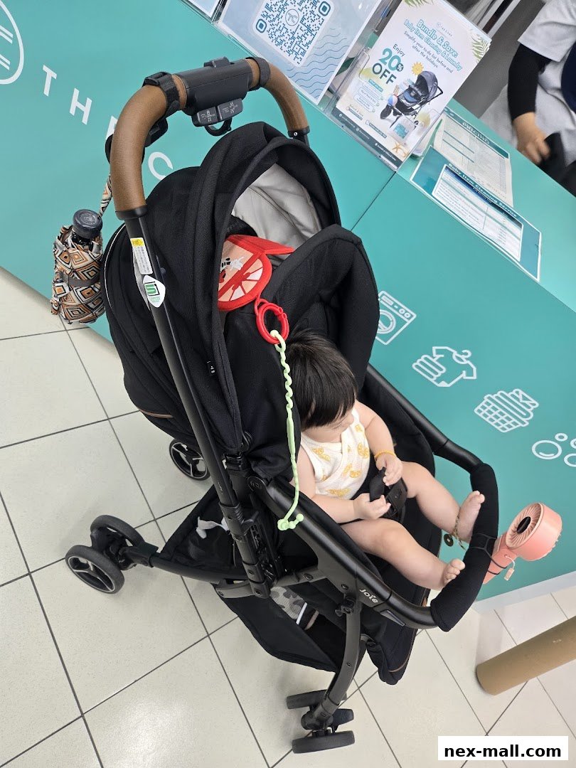 A baby sits in a stroller in front of a teal counter with laundry service information.
