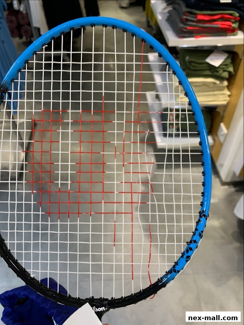 Close-up of a blue and black badminton racket with white and red strings.